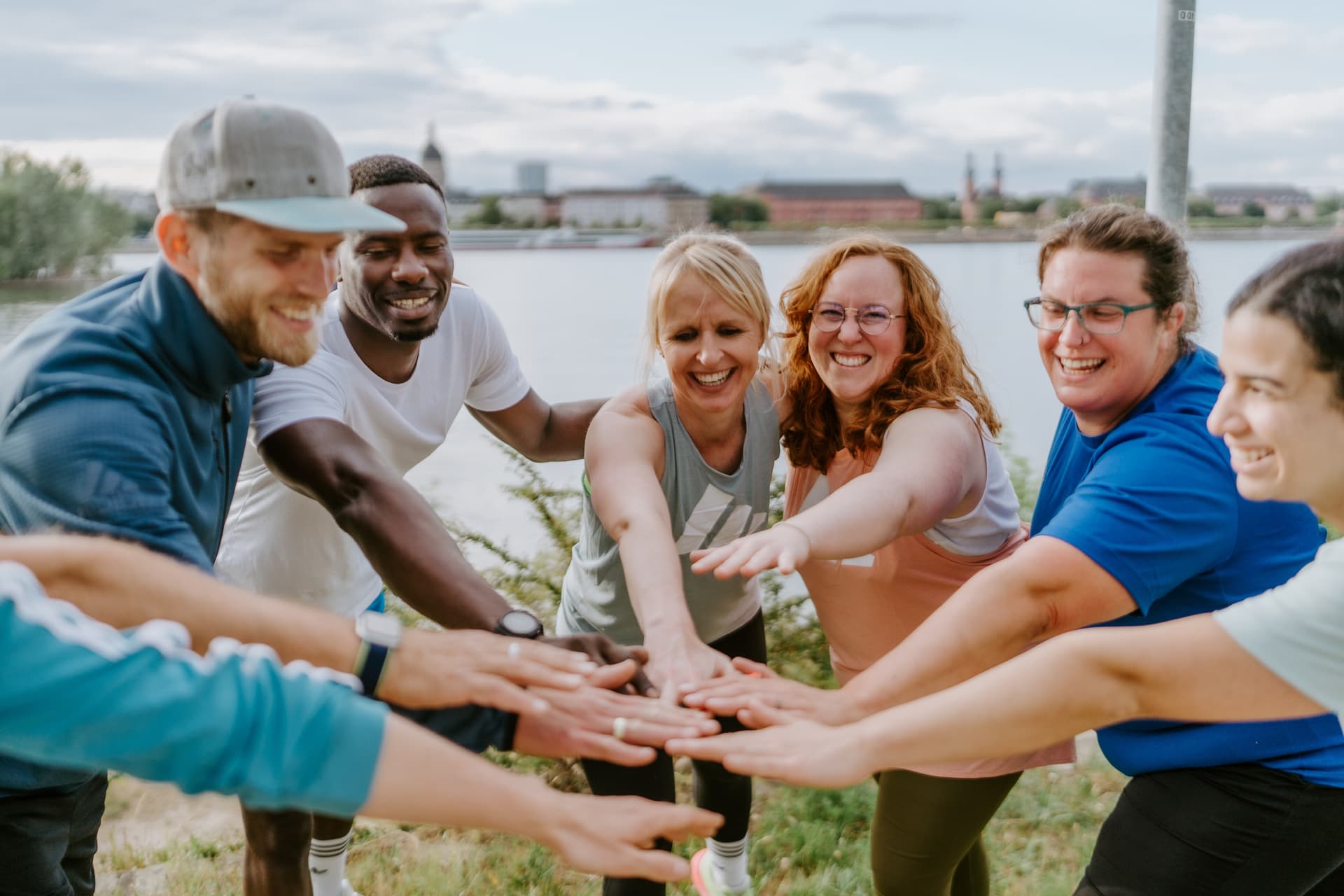 Gruppe von Outdoor Bootcamp-Teilnehmern feiert gemeinsam nach einem intensiven Training in Düsseldorf, Unterbacher See. Teamspirit und Motivation beim Sport an der frischen Luft.