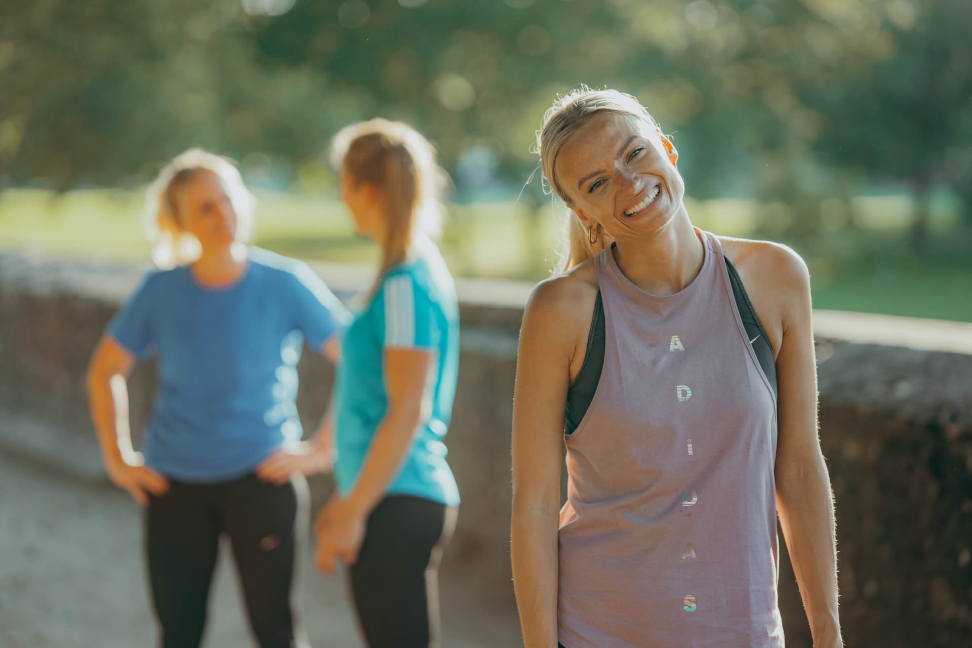 Eine lachende Bootie. Im Hintergrund redet eine Trainerin mit einer Teilnehmerin.