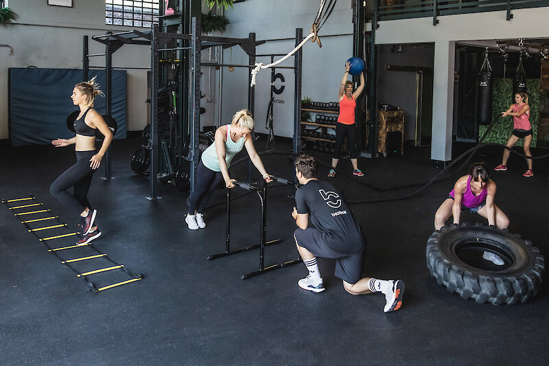 Zirkeltraining Indoor: Gruppe führt unterschiedliche Kraft- und Ausdauerübungen im Studio aus.