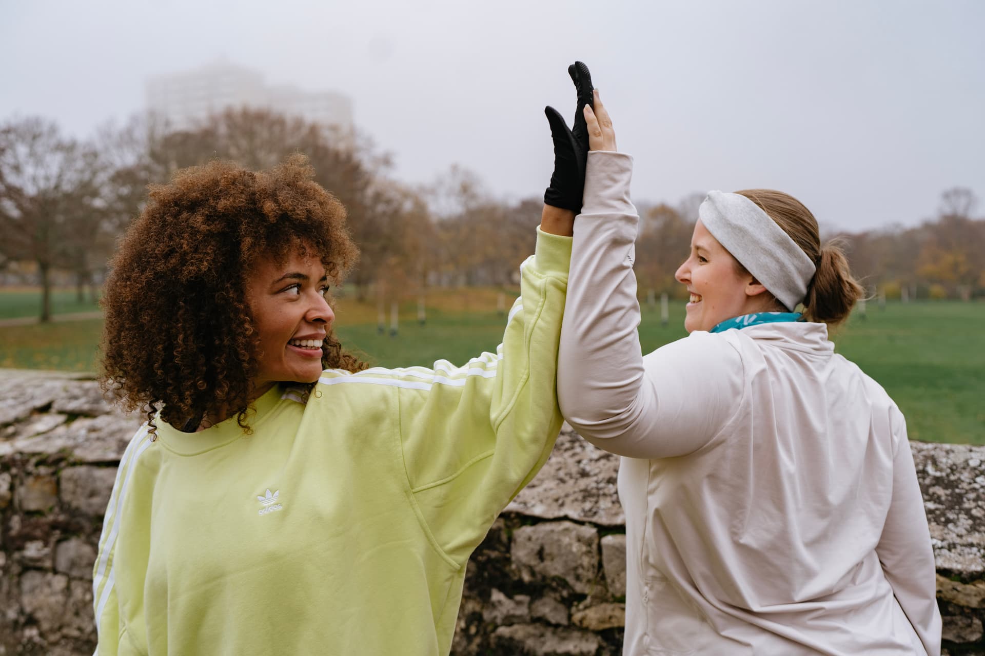 Zwei Frauen dehnen ihren Schultergürtel beim Workout in der Natur