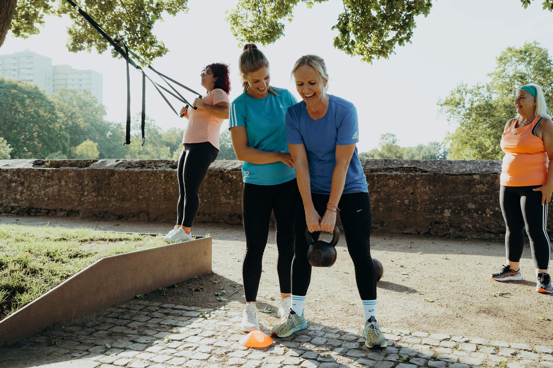 Die Trainerin korrigiert eine Teilnehmerin bei den Kettlebell Swings