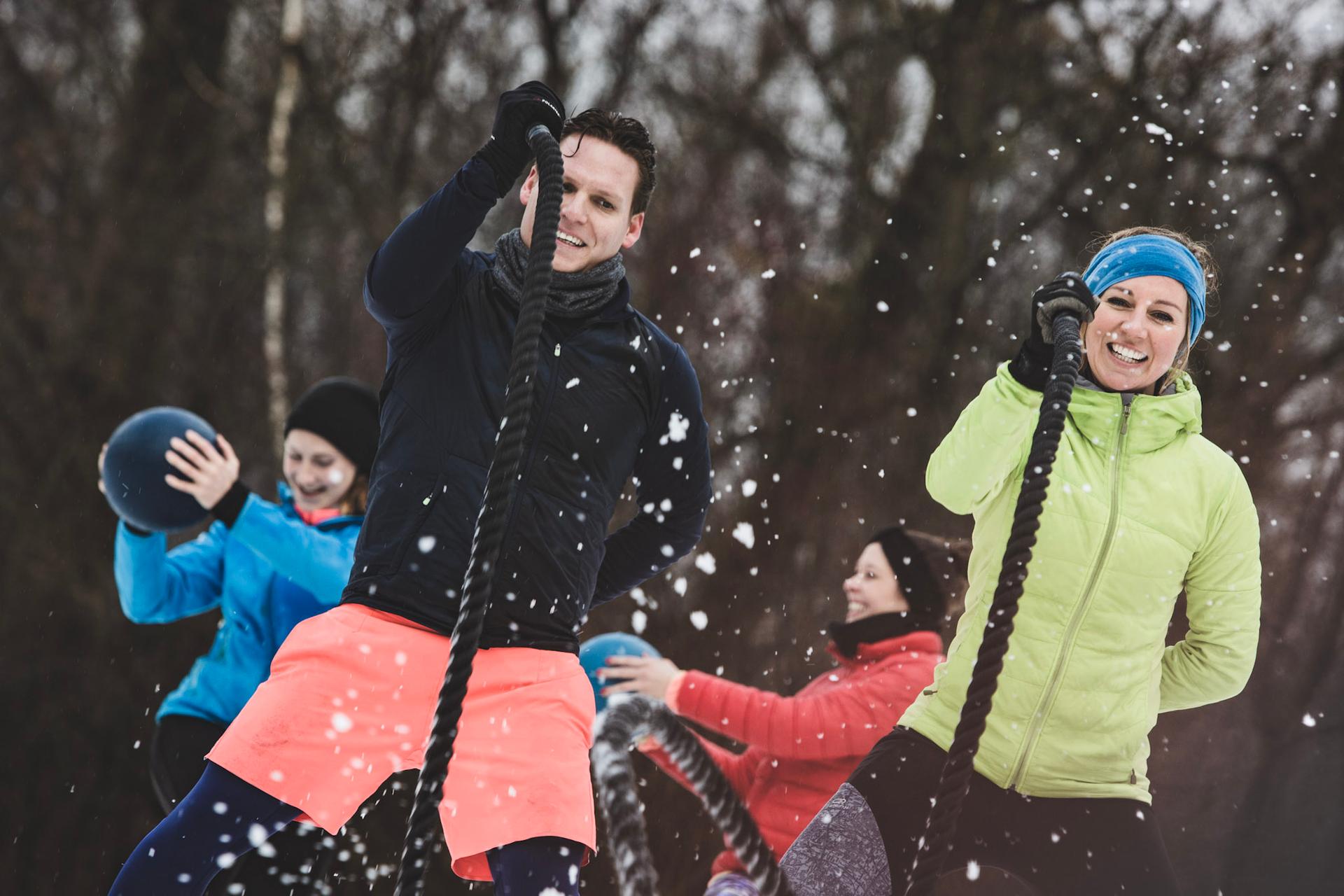 Zwei Menschen trainieren im Schnee an den Battleropes