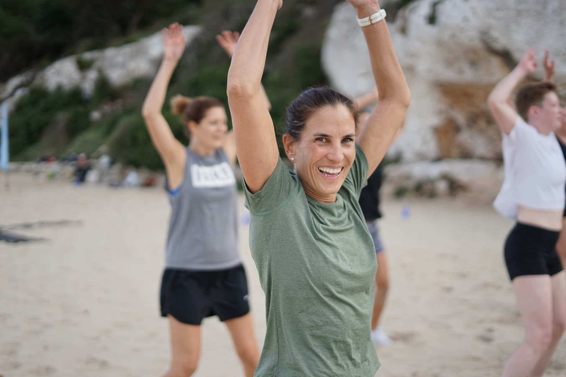 Lächelnde Frau die Hampelmänner im Fitness Retreat macht