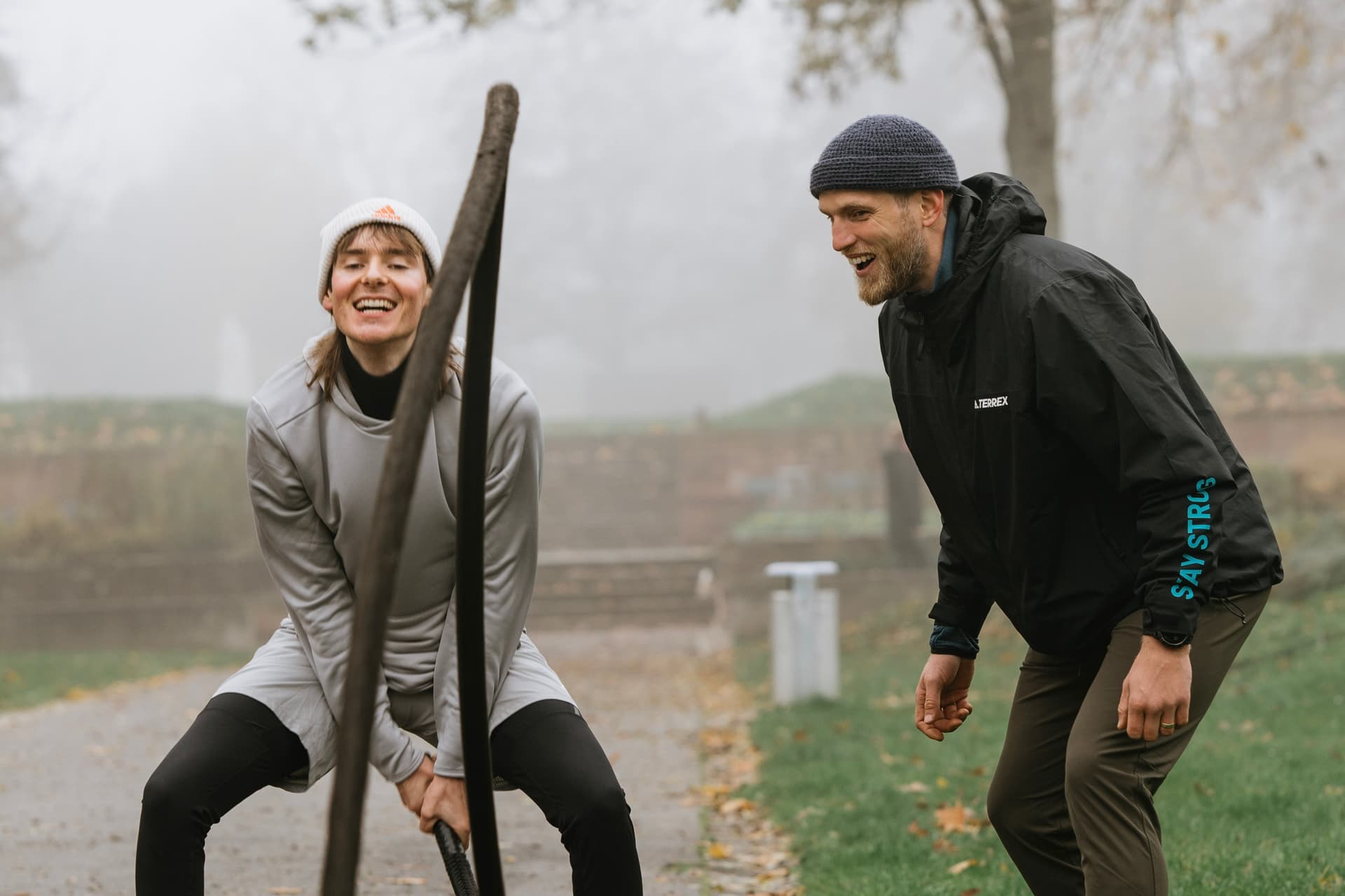 Ein Bootcamp Teilnehmer wird an den Battle Ropes vom Personal Trainer angefeuert