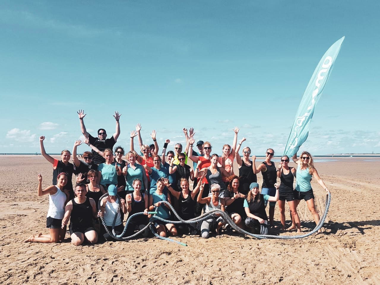 Glückliche Teilnehmer nach einer anstrengenden Sporteinheit im Sand