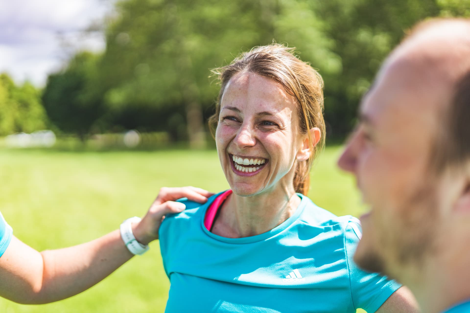 Lachende Personal Trainerin beim Training im Grünen